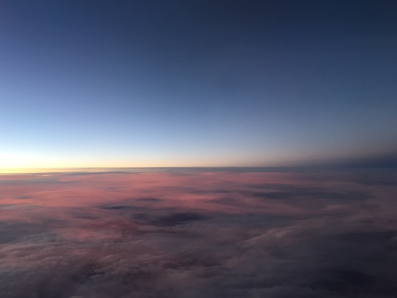 Image of sky taken from plane showing pink clouds and transition between day and night